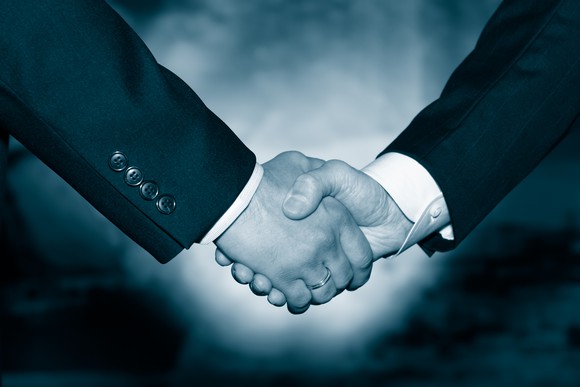 Businessmen shaking hands, as if in a buyout agreement. 