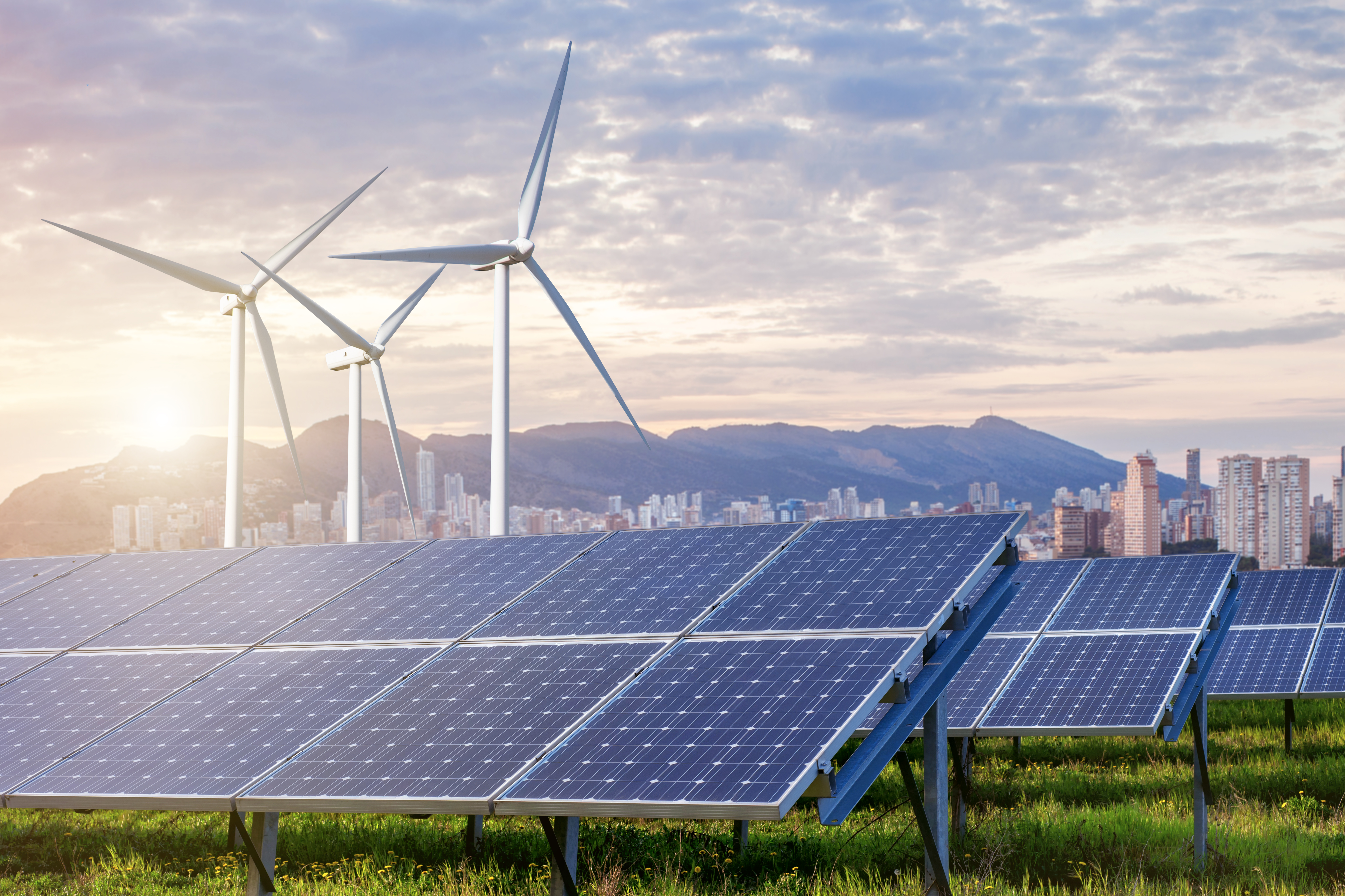 Solar and wind farm with a city in the background.