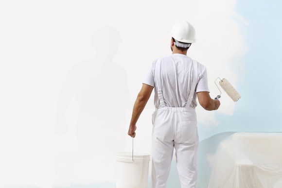 Painter painting a wall white.