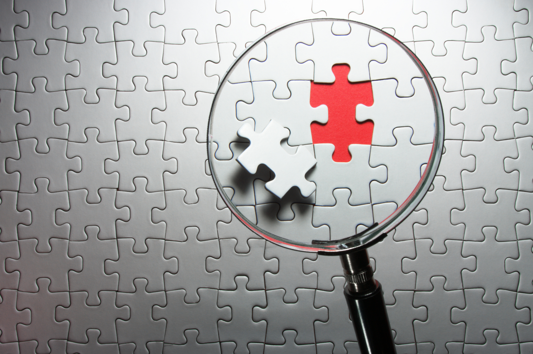 Missing jigsaw puzzle piece under magnifying glass