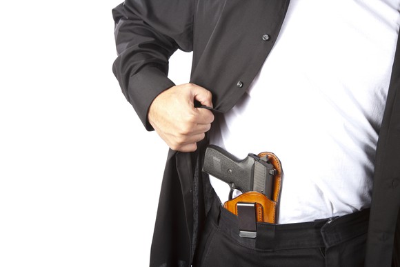 Man revealing a concealed carry weapon in a hip holster
