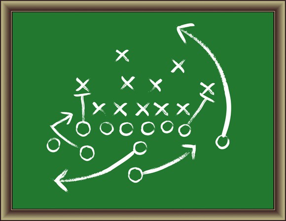 Football play diagrammed on a green chalkboard