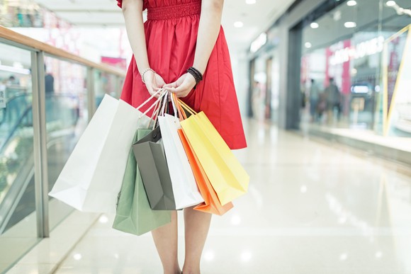 Young woman in red dress carrying shopping bags in upscale shopping mall.