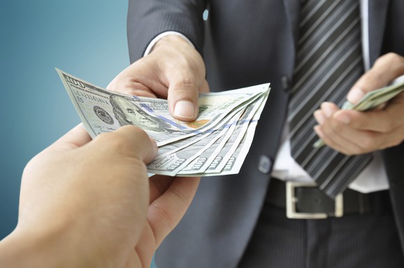 Wealthy individual handing over money, implying he's paying tax.