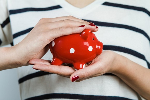 Woman holding small piggy bank in her hands.