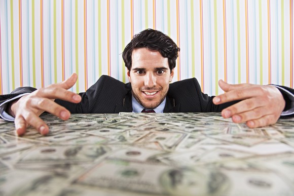 Businessman admiring a pile of cash on his table.