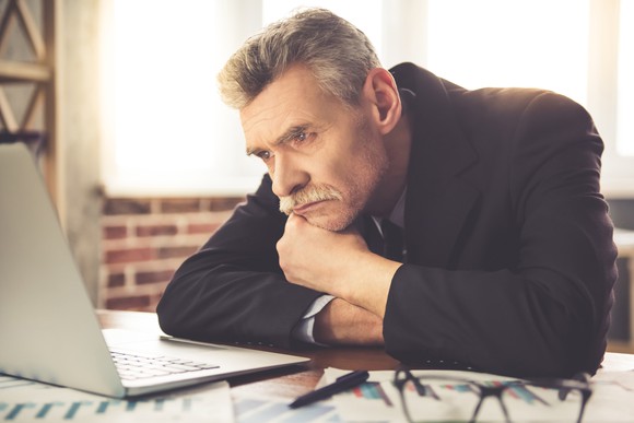 Tired businessman looking at his computer.