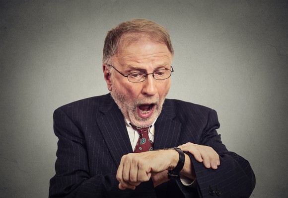 Man in suit looking at watch and alarmed at the time