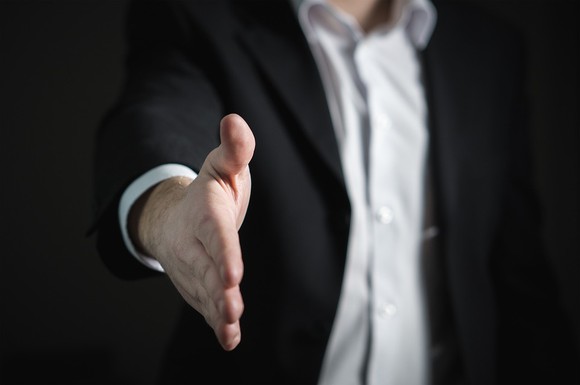 Business man extending arm to offer a hand shake