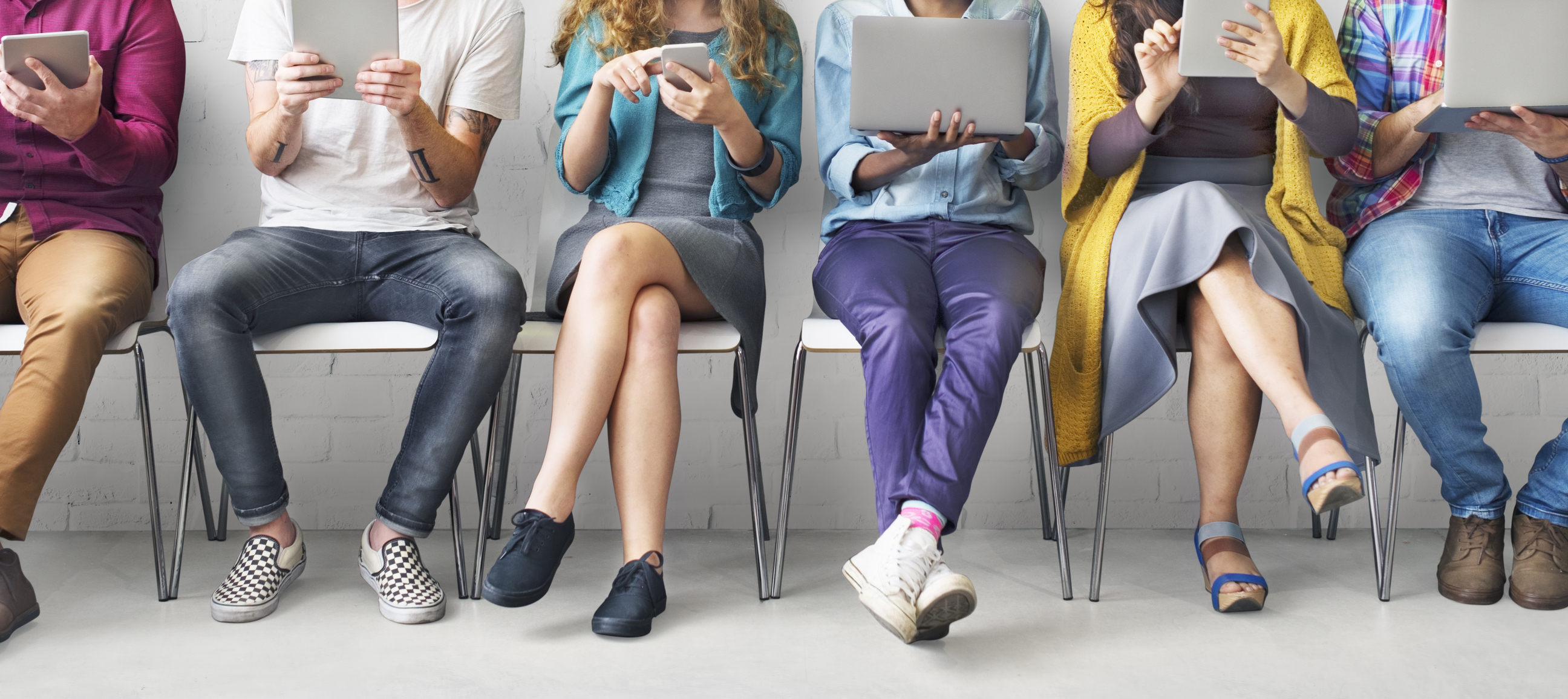 Seated people looking at laptops, tablets, and smartphones