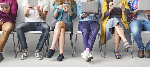 Seated people looking at laptops, tablets, and smartphones