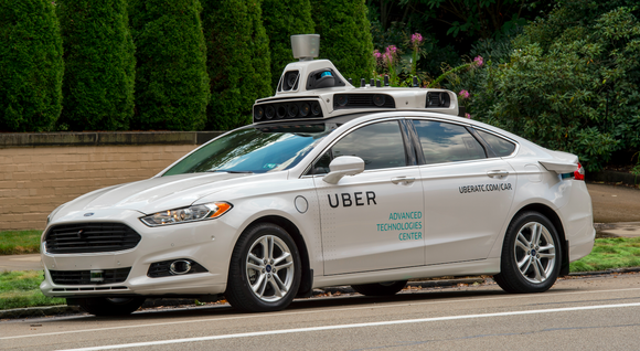 A white Ford Fusion sedan equipped with Uber's self-driving sensors.