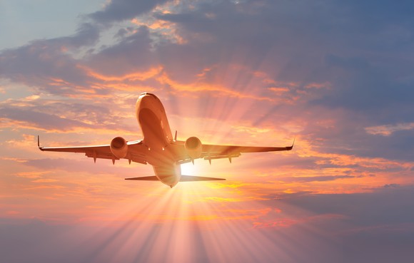 An airliner flying in front of the setting sun