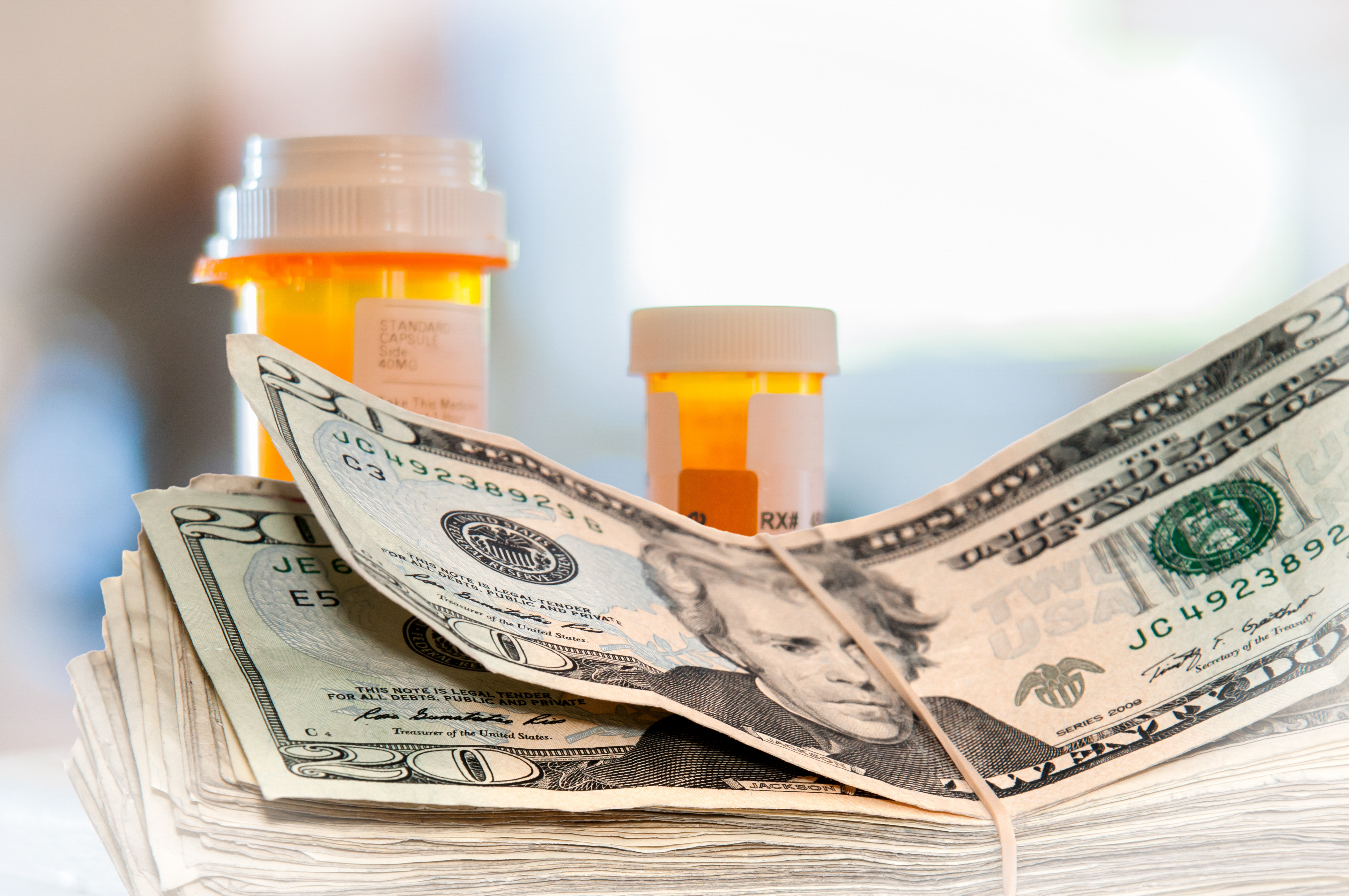 A stack of  $20 bills with two pill bottles in the background