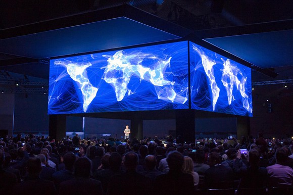 Mark Zuckerberg on stage under visualization of a connected world