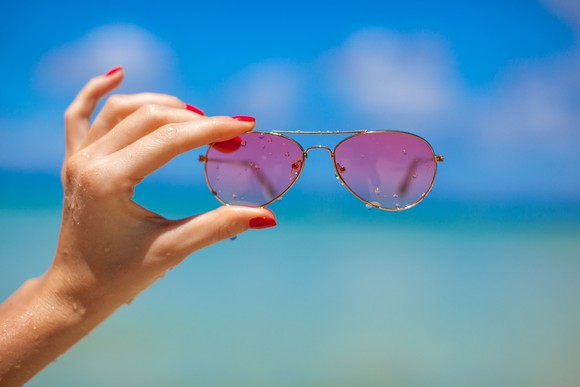 Hand holding rose-colored glasses