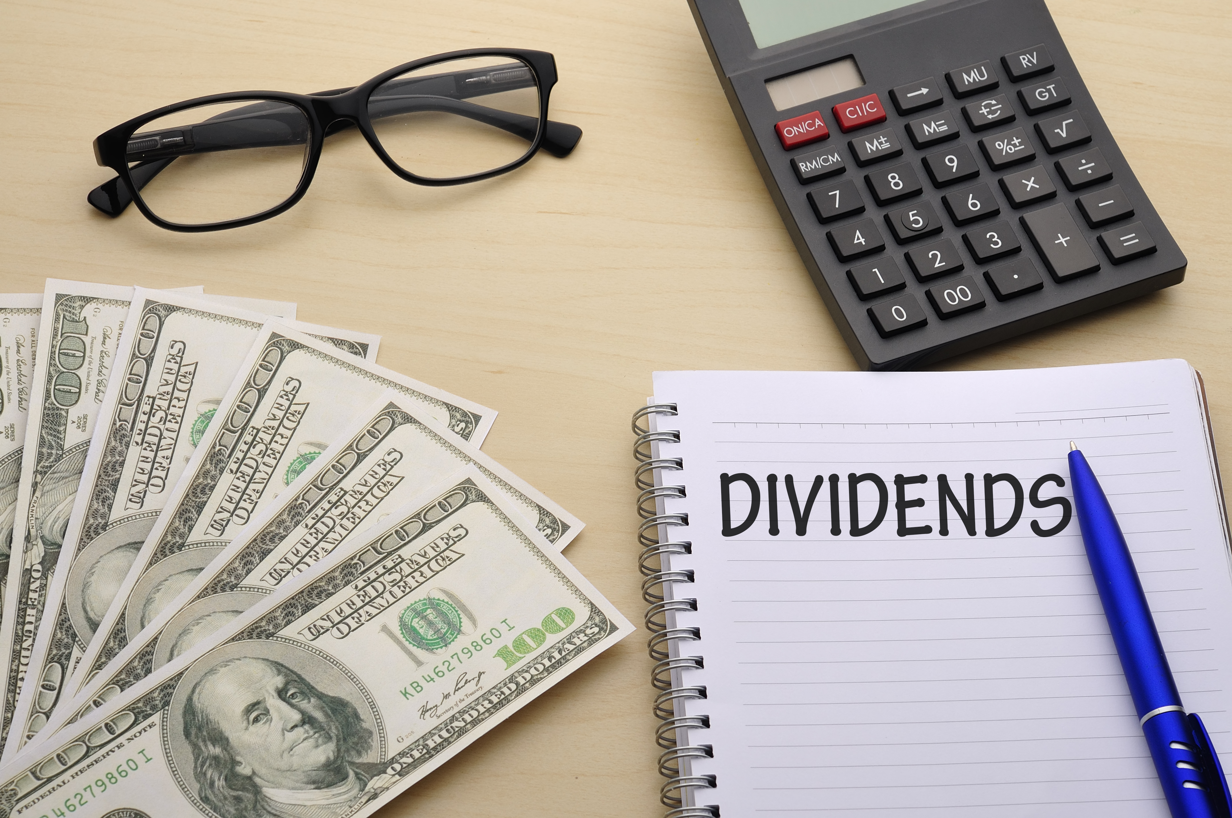 word "dividends" on notepad with money