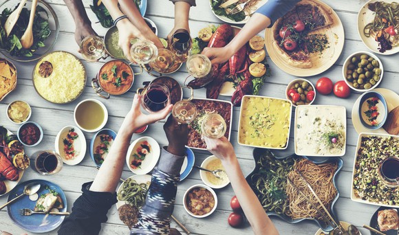 Friends sitting around table covered in food