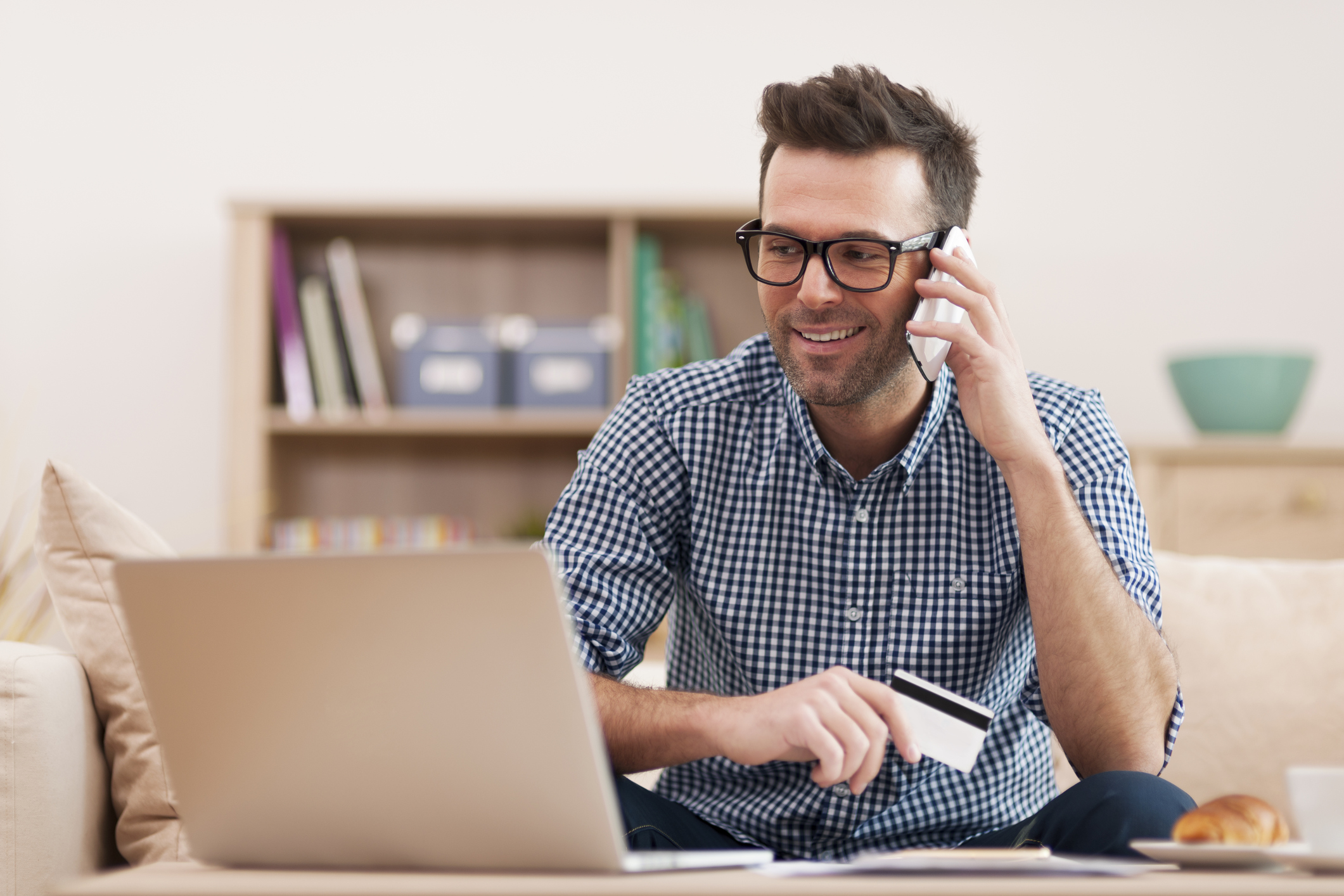 Man on laptop with phone and credit card.