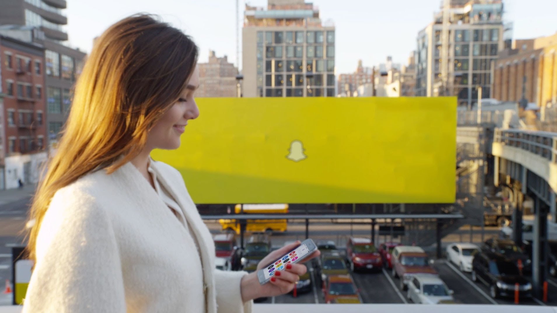 A woman using the Snapchat app in front of a large sign with the Snap logo.
