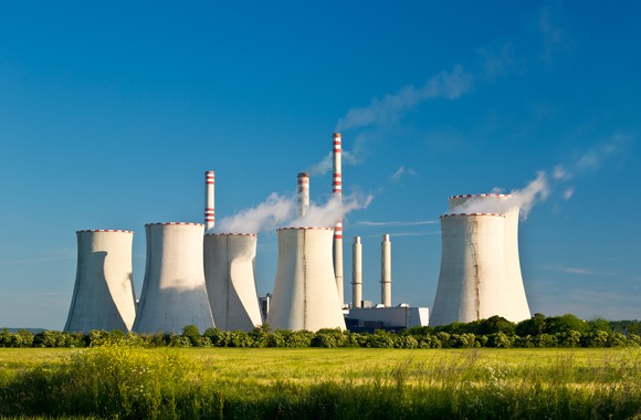 Power plant with smoke coming out of smokestacks on a sunny day.