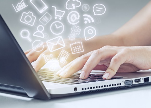 A woman types on a laptop keyboard, and a cloud of icons "floats" out.