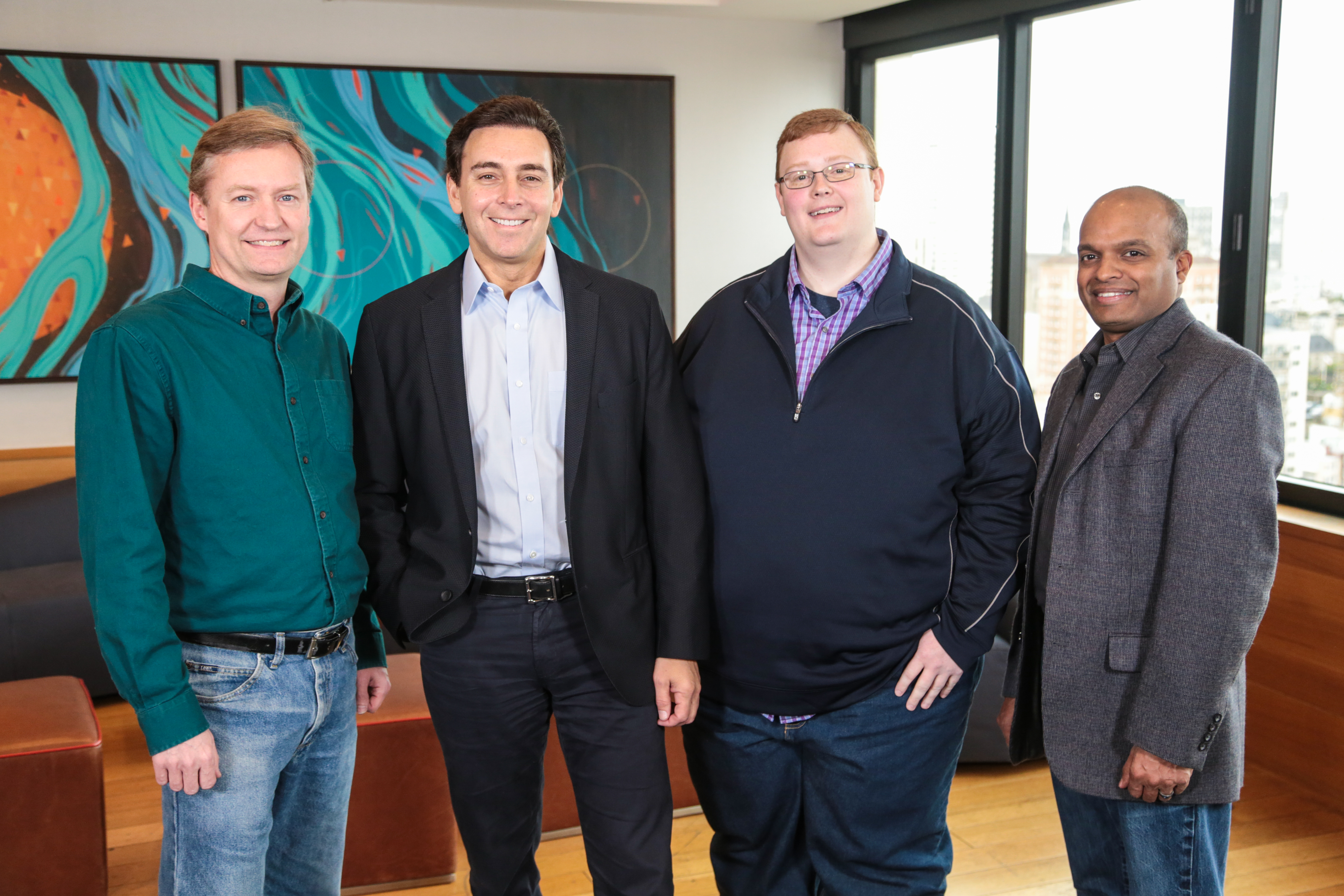 The four men are standing in a conference room.