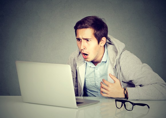 Shocked man staring at a laptop.