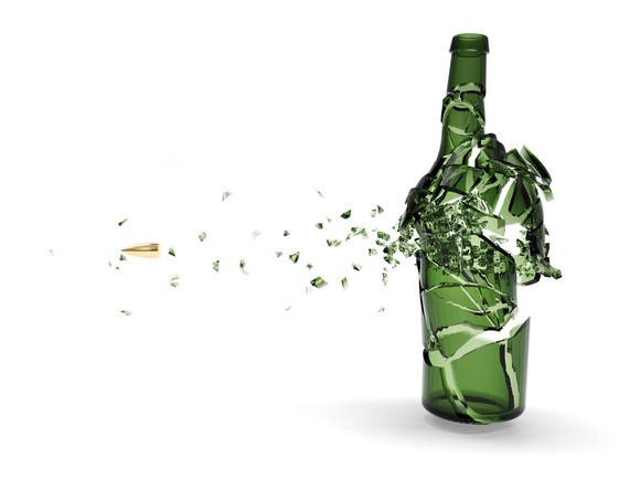 Bullet shattering a green beer bottle