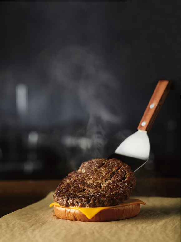 A fresh-cooked burger is placed on a bun.