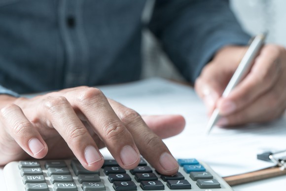 Man with calculator adding up expenses.