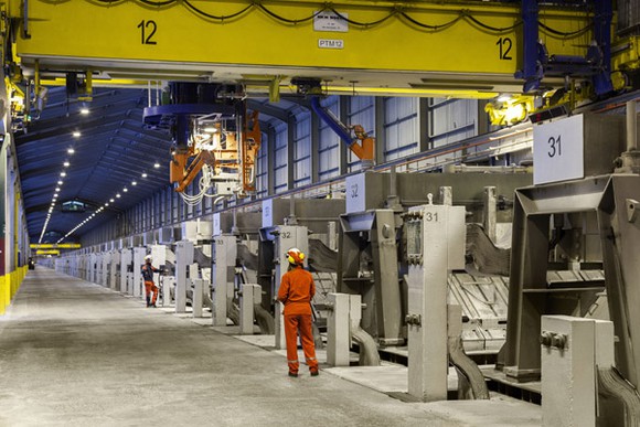A Century Aluminum employee standing in a factory aisle lined with machines.