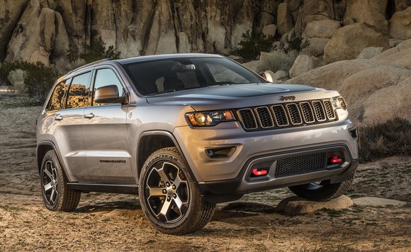 A silver Jeep Grand Cherokee SUV in a rocky off-road setting.