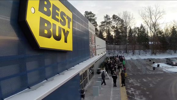 Customers waiting outside of a Best Buy store.