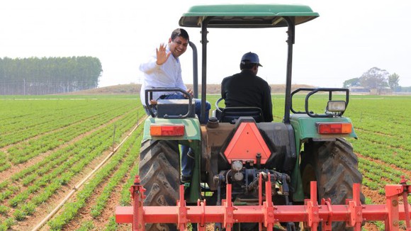 A microsoft employee rides on the back of a tractor in India.