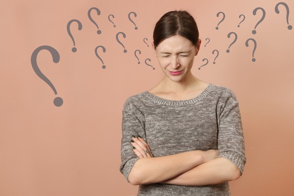 A young woman looking confused, with question marks around her.