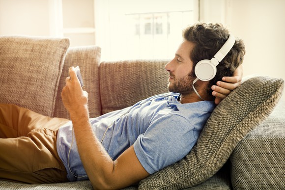A man listens to music on his smartphone with wired headphones.