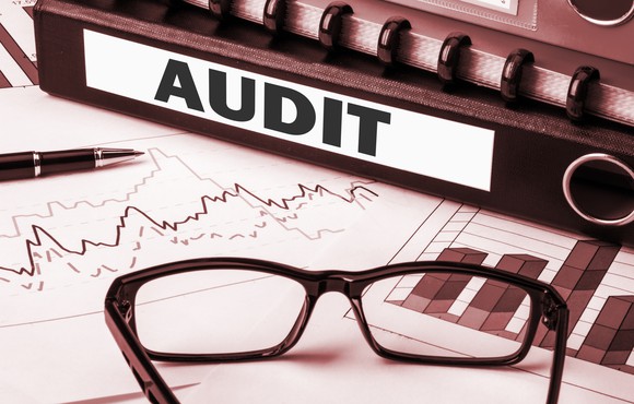 Documents and glasses with an audit sign adjacent