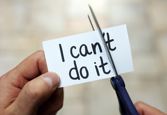Person cutting up sign reading "I can't do it."
