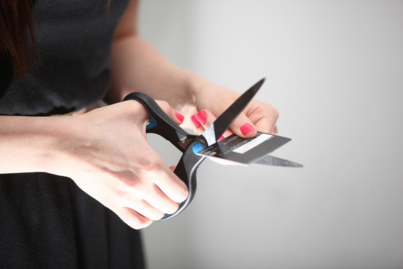 Woman cutting credit card in half.