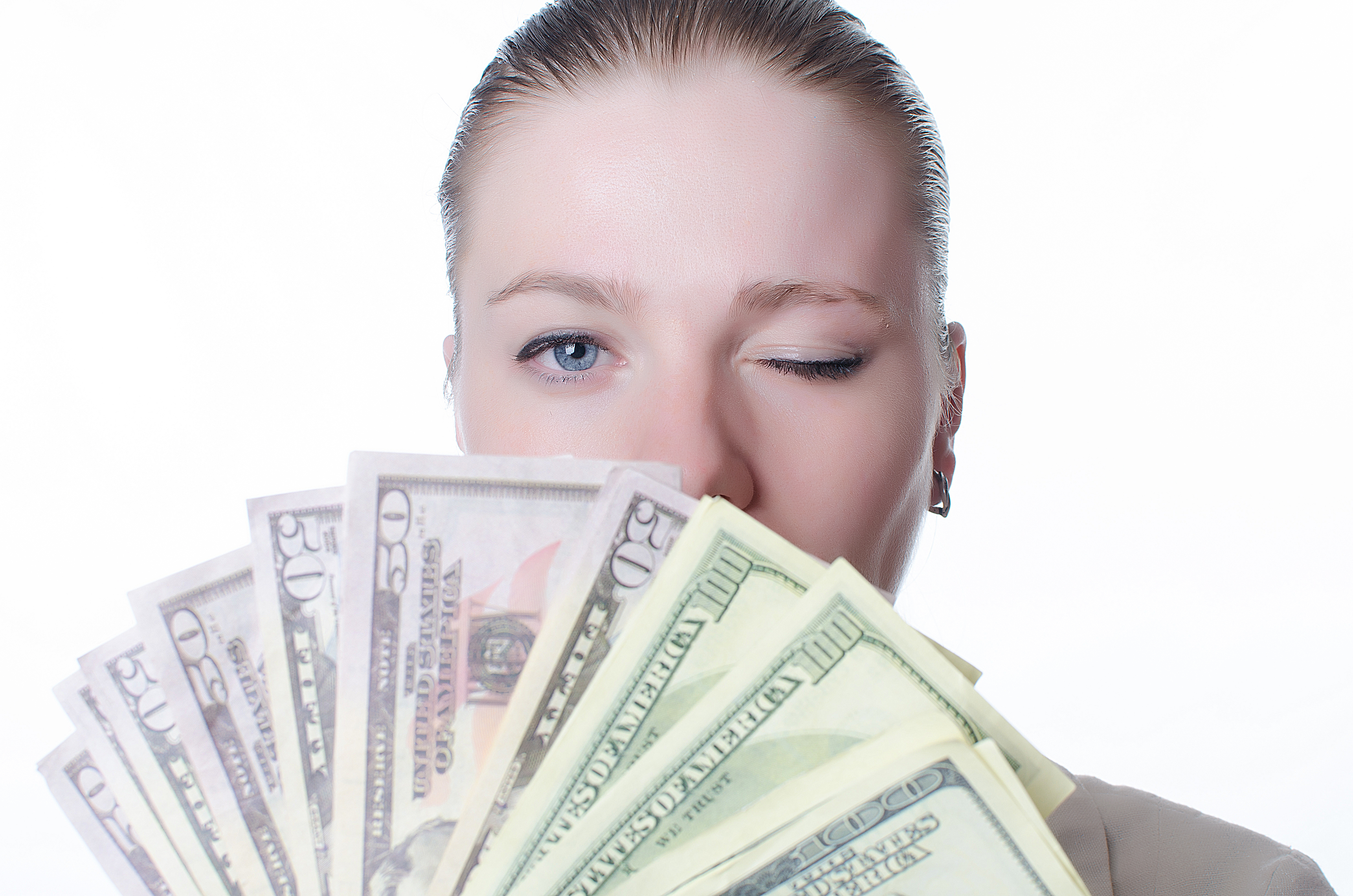 Woman holding fanned out money and winking.