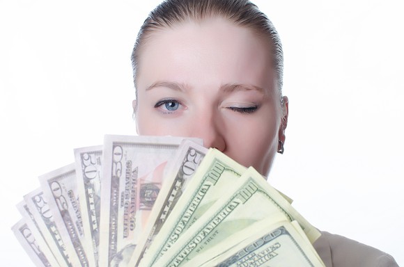 Woman holding fanned out money and winking.