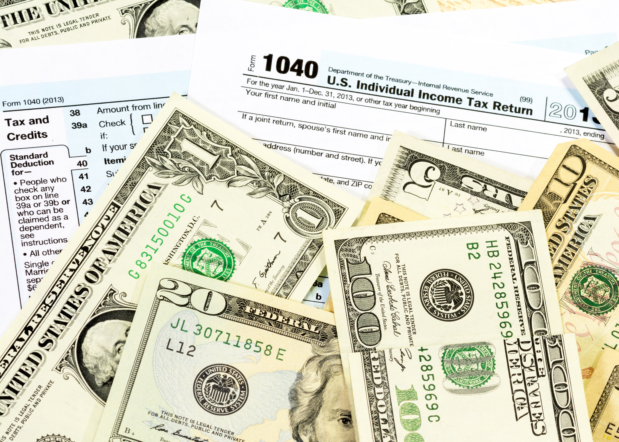 Tax forms with money on top.