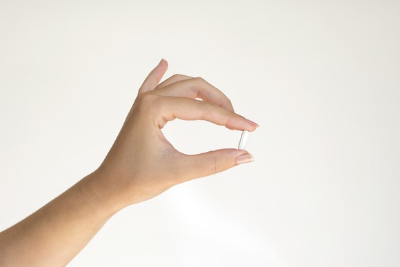 Hand holding white pill