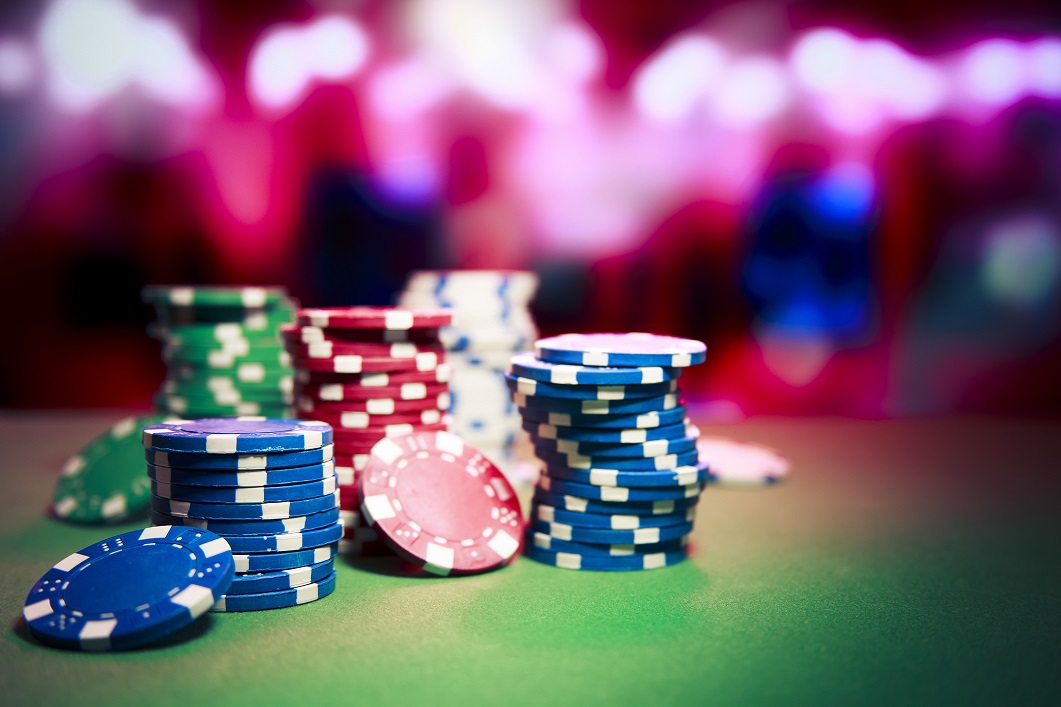 Casino chips on a table in front of casino games.