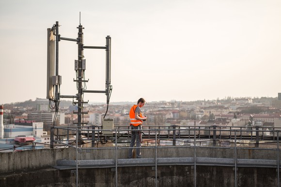 A telecom worker tests a mobile phone company's cell tower on the top of a building.