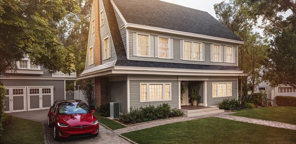 Home with Tesla solar tiles and a Model X parked in the driveway