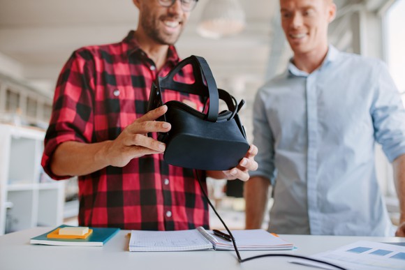 Two guys looking at a virtual reality headset.