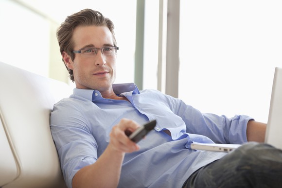 A man in glasses watching TV.