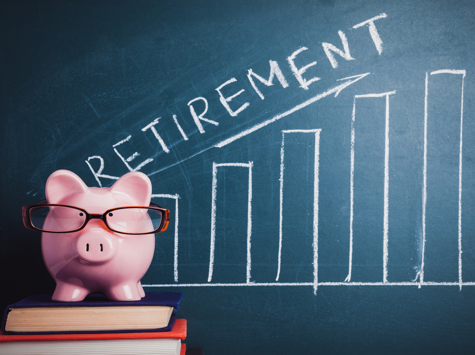 Piggy bank in front of blackboard on which is a rising bar graph and the word retirement